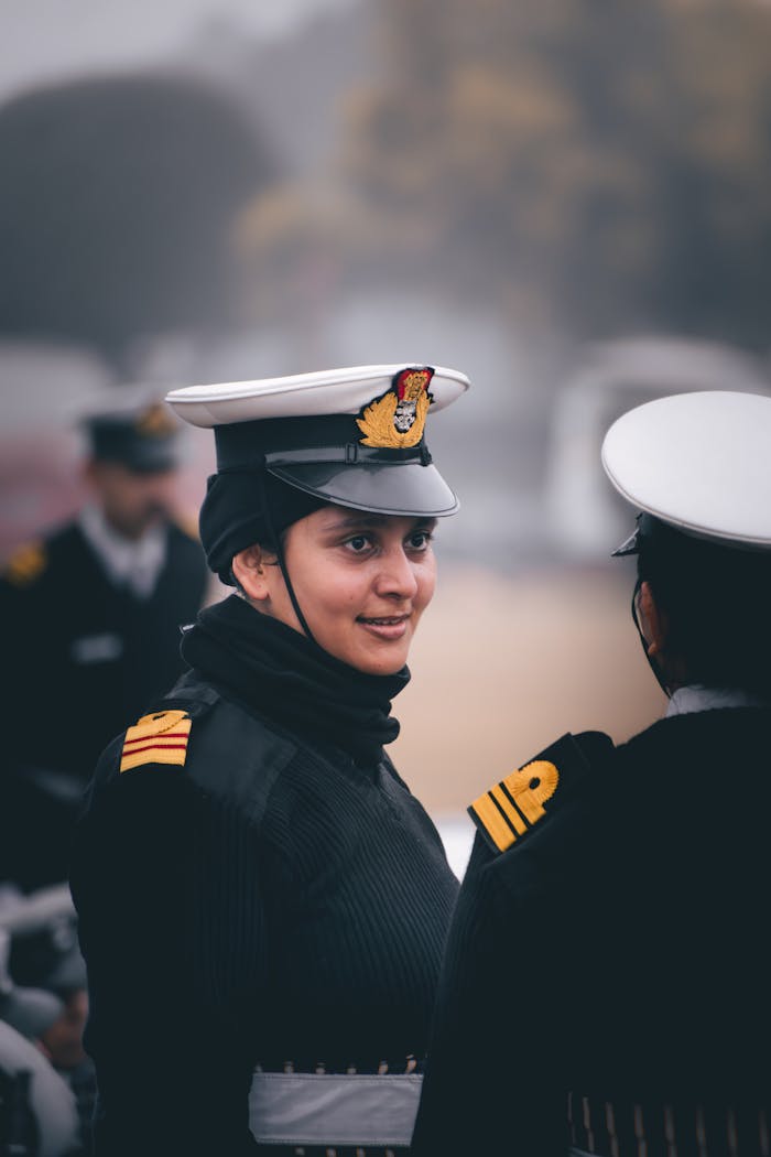 Two female naval officers in uniform having a discussion outdoors.